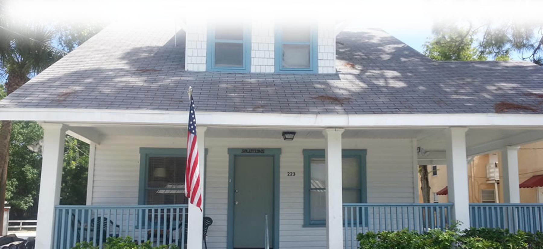 A house with american flag on the front porch.